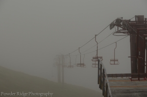 Bright red chairs of a chair lift at Arctic Valley hold a quiet vigil in the mist, waiting for the snows of winer to again bring them life.